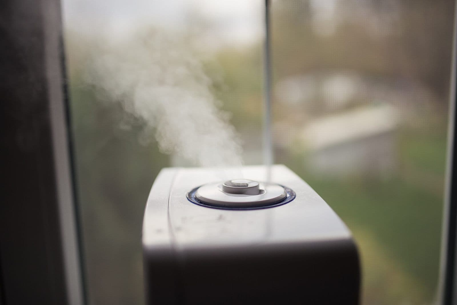 Close-up of a room humidifier releasing a plume of water vapor