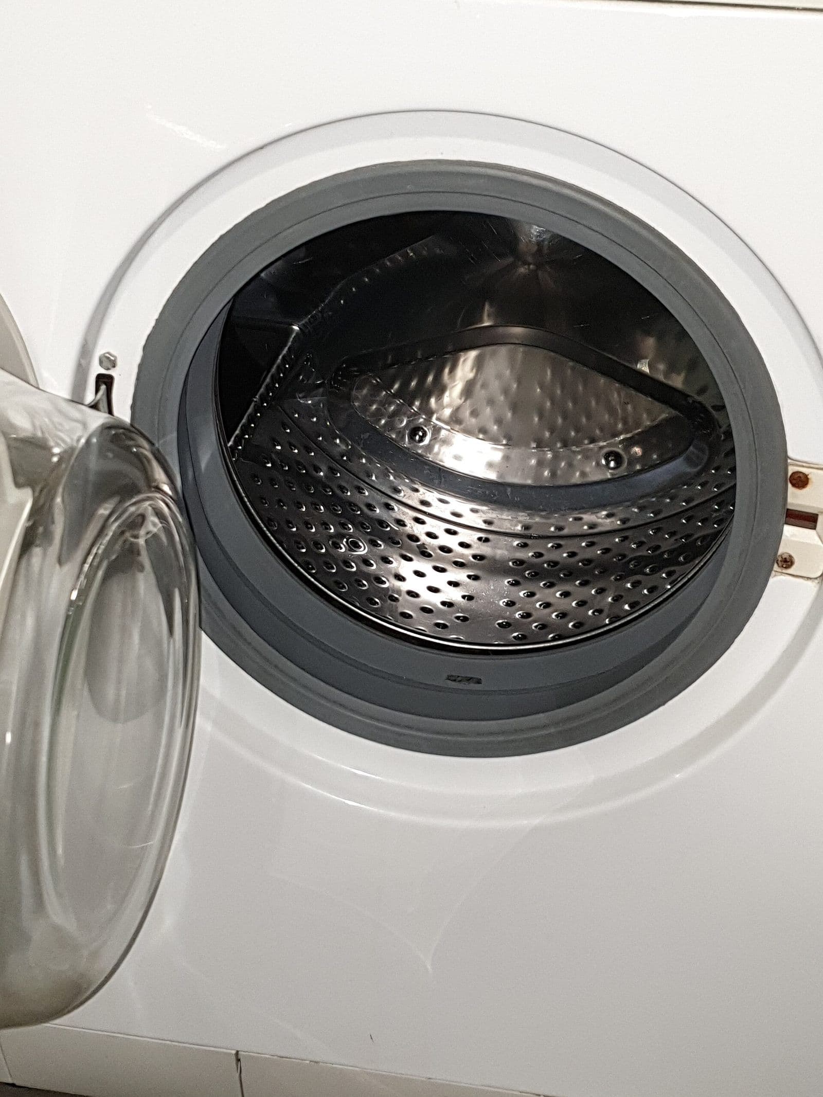 Open front-loading washing machine showing the drum and rubber door gasket