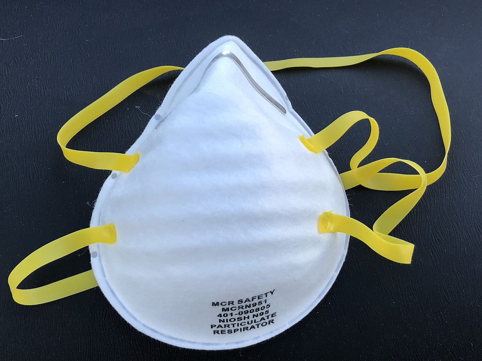 A white NIOSH-approved N95 particulate respirator with yellow straps