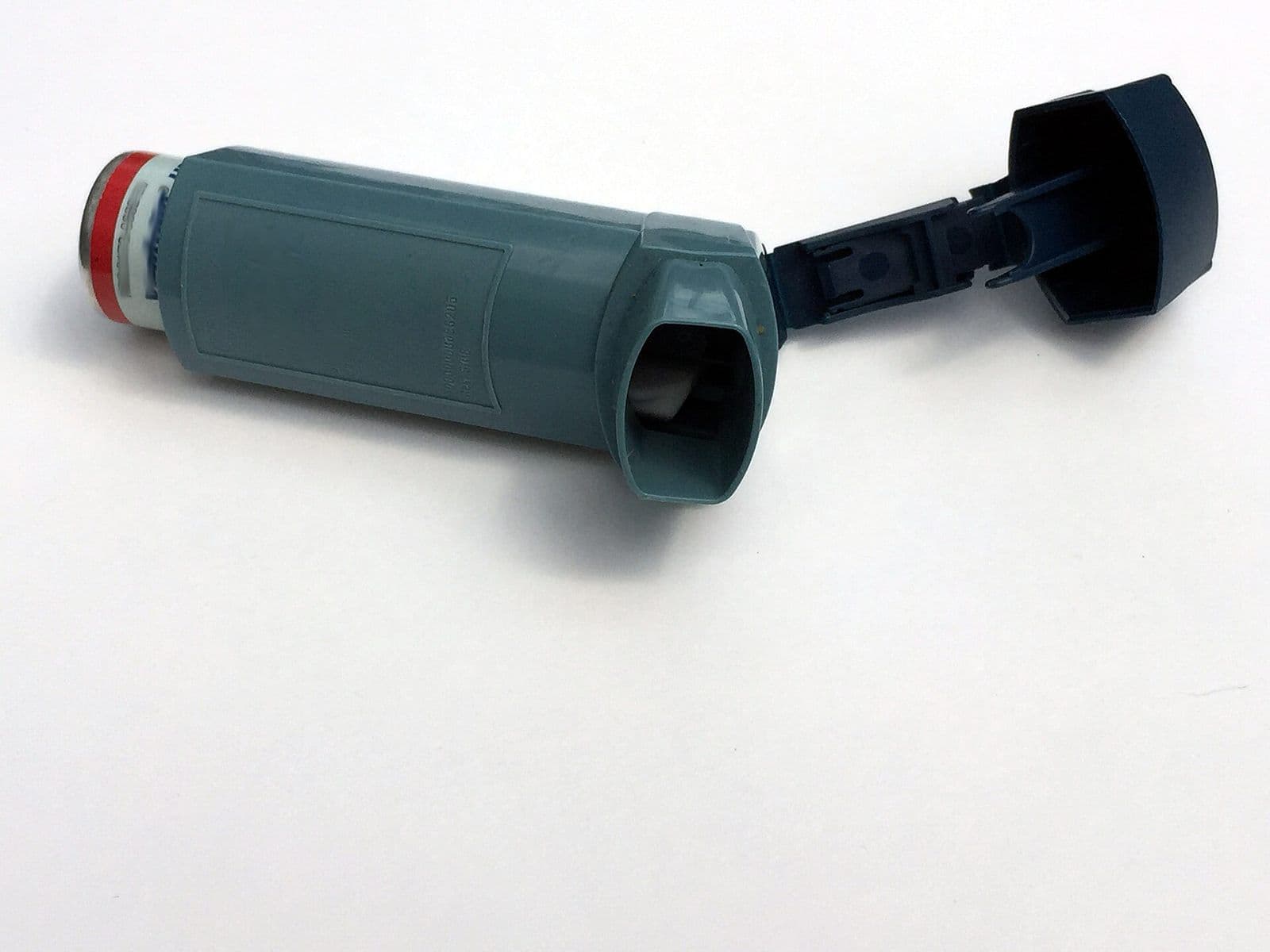 An asthma inhaler with its cap open on a white background