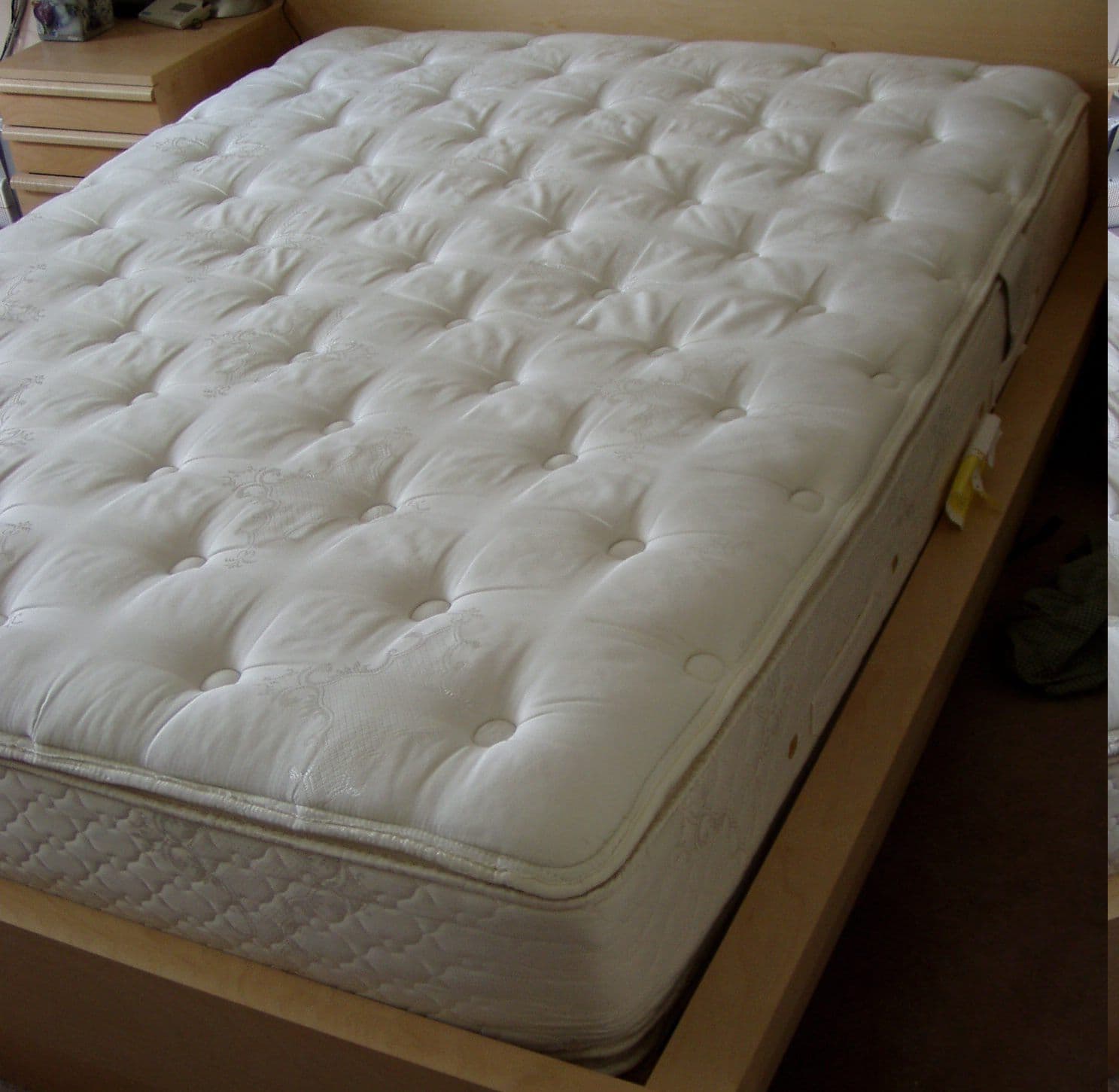 A bare white pillowtop mattress on a bed frame